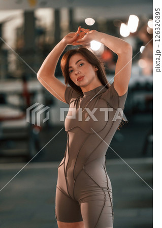 With hands up. Standing and posing. Beautiful woman with sport body type is in the gym With hands up. Standing and posing. Beautiful woman with sport body type is in the gym 126320895