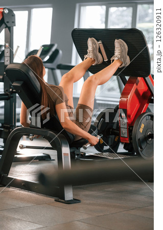 Doing exercises for the legs. Beautiful woman with sport body type is in the gym Doing exercises for the legs. Beautiful woman with sport body type is in the gym 126320911