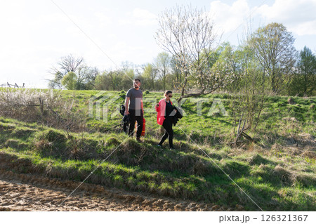 Couple enjoys a sunny afternoon stroll along a scenic riverside path surrounded by fresh greenery and blooming trees in early spring Couple enjoys a sunny afternoon stroll along a scenic riverside path surrounded by fresh greenery and blooming trees in early spring 126321367