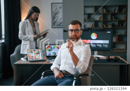 Woman is behind the man. Two employees are working together in the modern office 126321394