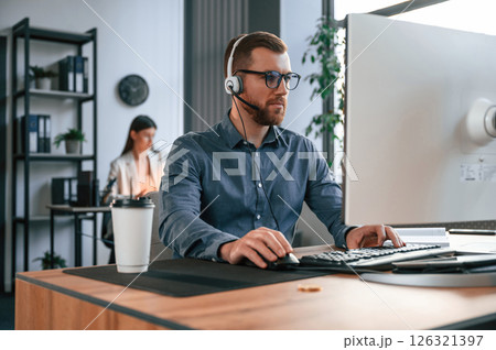 Man is using computer. Two employees are working together in the modern office Man is using computer. Two employees are working together in the modern office 126321397