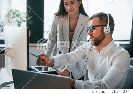 Analyzing information that is on the screen. Two employees are working together in the modern office Analyzing information that is on the screen. Two employees are working together in the modern office 126321824