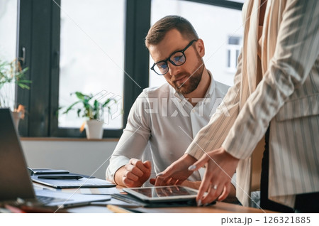 Woman is holding tablet, analysing information. Two employees are working together in the modern office 126321885