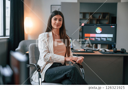 Sitting on the chair. Designer's software on the screen. Woman is working in the modern office with computer Sitting on the chair. Designer's software on the screen. Woman is working in the modern office with computer 126321925