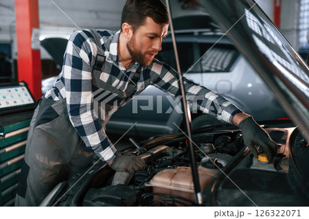 Focused on work. Repairing the car. Man in uniform is in the auto salon 126322071