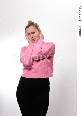 Woman experiencing discomfort, holding her head with hands, eyes closed, pained expression. Woman experiencing discomfort, holding her head with hands, eyes closed, pained expression. 126322491