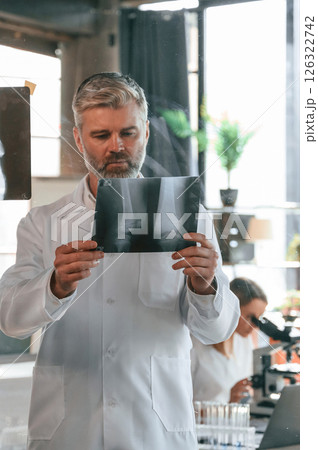 Bones pictures on the x-ray. Two clinic workers are indoors together. Senior man with young woman Bones pictures on the x-ray. Two clinic workers are indoors together. Senior man with young woman 126322742