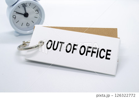 Out Of Office text on white notepad with alarm clock on white background. Away from office concept 126322772