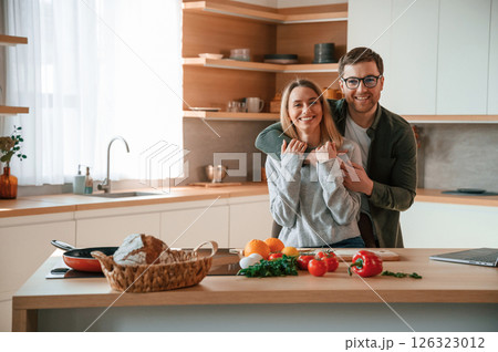 Embracing each other. Young couple is on the kitchen together Embracing each other. Young couple is on the kitchen together 126323012