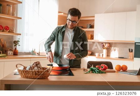Preparing the food. Handsome man is on the kitchen at daytime 126323076