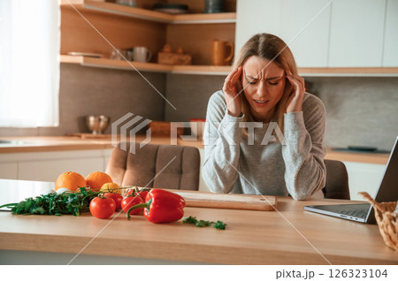 Tired, having headache. Beautiful young woman is on the kitchen 126323104