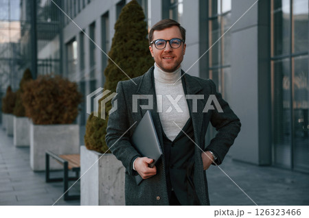 Handsome man in formal clothes is outdoor near the business building 126323466