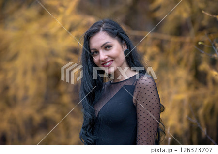 Portrait of a beautiful young woman with long black hair in the autumn park Portrait of a beautiful young woman with long black hair in the autumn park 126323707