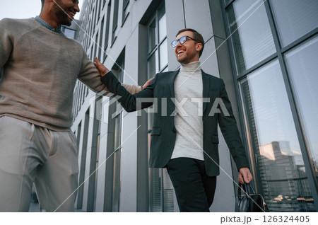 Conception of collaboration. Businessman in formal clothes is with black man outdoors in the city 126324405