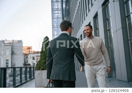 Conception of collaboration. Businessman in formal clothes is with black man outdoors in the city Conception of collaboration. Businessman in formal clothes is with black man outdoors in the city 126324408
