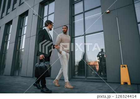 Businessman in formal clothes is with black man outdoors in the city 126324414