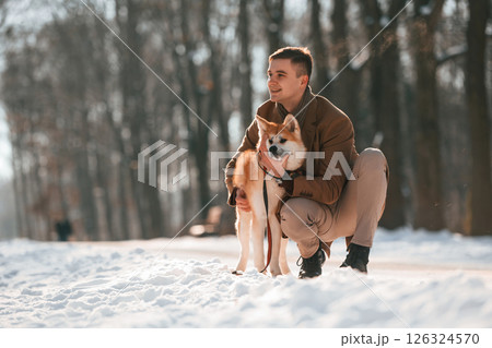 Sitting and embracing the dog. Man having a walk with his akita inu dog outdoors in the park at winter 126324570