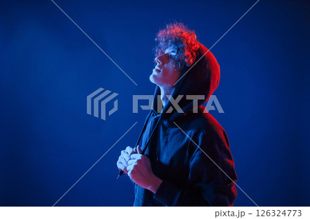 View from the side. Young man with curly hair is indoors illuminated by neon lighting 126324773
