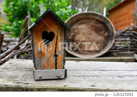 Charming Wooden Birdhouse With Heart-Shaped Opening Amidst a Rustic Outdoor Setting in Spring 126325891