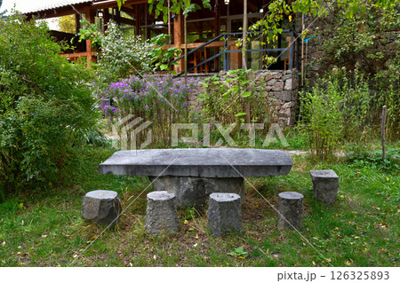 Rustic Stone Table Surrounded by Greenery at a Peaceful Outdoor Location in Autumn 126325893