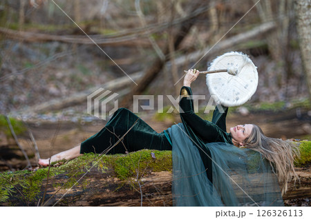 Woman playing a drum in a forest. Shallow depth of feld 126326113