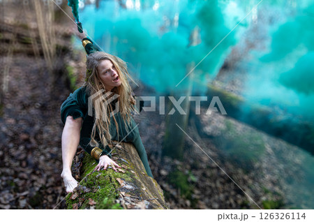 Woman posing with blue smoke in forest. Shallow depth of feld 126326114