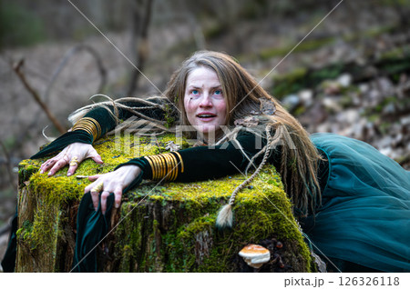Woman leaning on tree trunk in forest. Shallow depth of feld 126326118