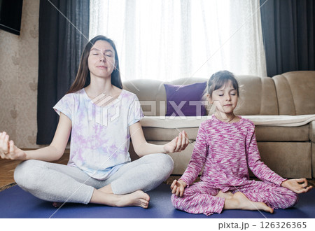 Mom and daughter doing yoga and meditation at home. Home workout together. Fun and active family time Mom and daughter doing yoga and meditation at home. Home workout together. Fun and active family time 126326365