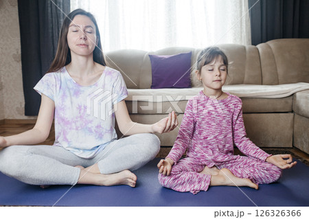 Mom and daughter doing yoga and meditation at home. Home workout together. Fun and active family time 126326366