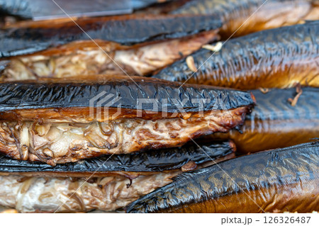 Smoked fish glimmers in the sunlight at a bustling market during midday in a coastal town 126326487