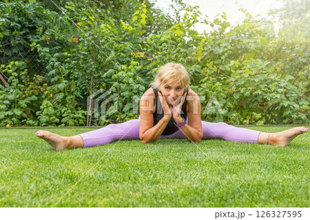 Flexible mature woman doing a leg split. Flexible mature woman doing a leg split. 126327595