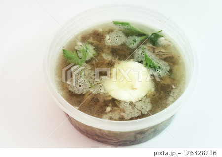 aspic with meat, eggs and fresh parsley, made with thick and rich nutritious bone broth, frozen in round transparent plastic food container 126328216