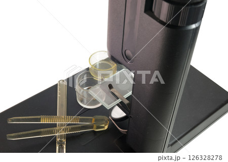 biological microscope, accessories, specimens in glass jars, transparent tweezers with ribbed handles, adjustment spatula-dropper. closeup 126328278