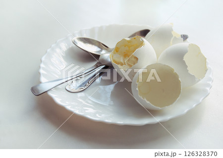 ending of morning meal of soft-boiled eggs in an elegant plate, with three teaspoons on it 126328370