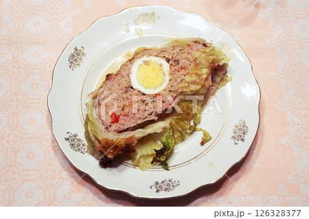 piece of meatloaf in Savoy cabbage leaves in a beautiful vintage serving plate. half an egg in the center of the cut, a lot of spiced minced meat, it looks delicious piece of meatloaf in Savoy cabbage leaves in a beautiful vintage serving plate. half an egg in the center of the cut, a lot of spiced minced meat, it looks delicious 126328377
