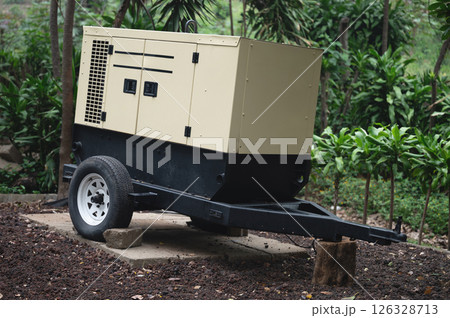 Portable generator positioned on plot surrounded by lush greenery in daylight 126328713