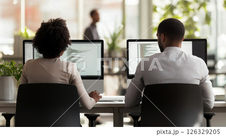 Two software testers african american young man and woman working in office with computer coding and pointing at monitor. 126329205