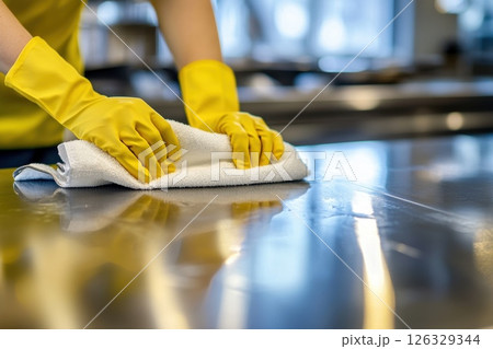 Chef in Yellow Gloves Cleaning Stainless Steel Countertop in a Commercial Kitchen. Chef in Yellow Gloves Cleaning Stainless Steel Countertop in a Commercial Kitchen. 126329344