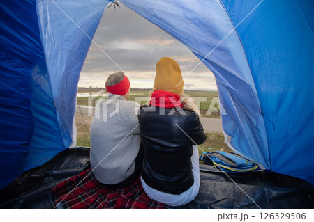 Active elderly Caucasian couple relaxing in a tent against the backdrop of autumn natural landscape. Man and woman tourists on a trip. 126329506