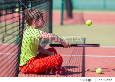 Boy athlete near tennis net with racket and ball. Children's sport. 126329662