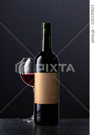 Bottle and glass of red wine on a black background. 126330023