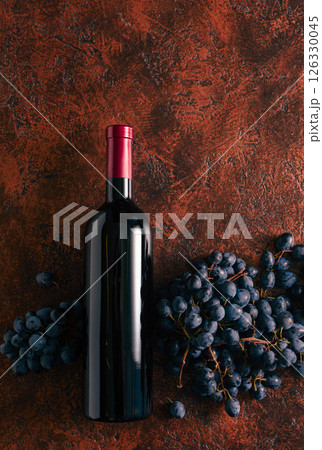 Blue grapes and bottle of red wine on a brown vintage background. 126330045