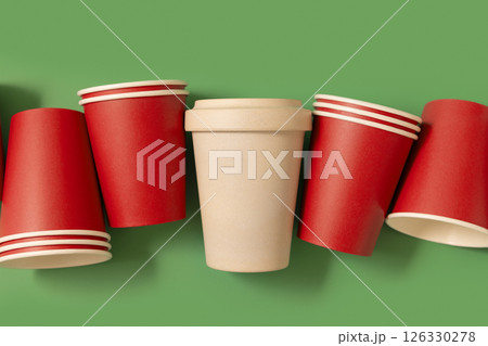 New red paper cups and beige reusable bamboo coffee cup on a green top view, mockup New red paper cups and beige reusable bamboo coffee cup on a green top view, mockup 126330278