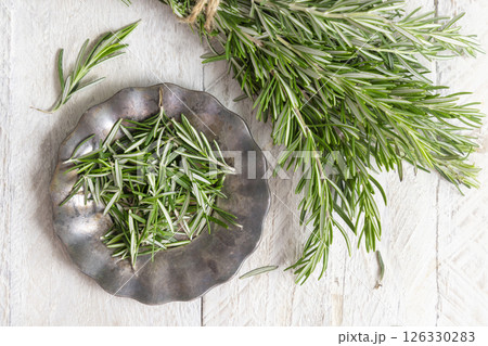 Fresh green rosemary sprigs on a plate on white rustic table top view. Aromatic herb for culinary Fresh green rosemary sprigs on a plate on white rustic table top view. Aromatic herb for culinary 126330283