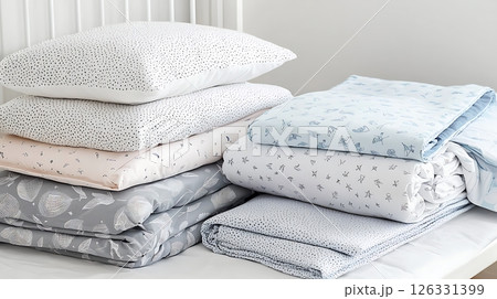 A stack of bedding with a blue and white blanket on top 126331399