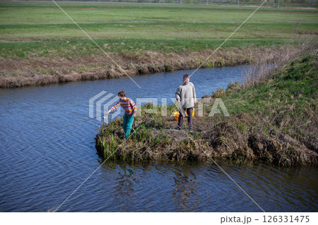 The boys are fishing on a small river. Friends go fishing in the summer. 126331475