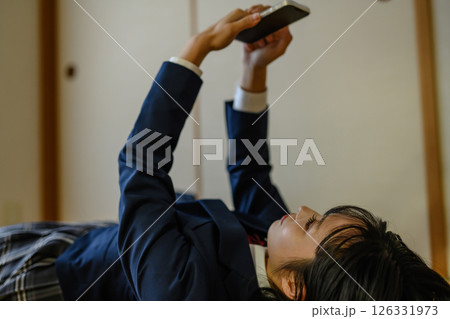 和室内で寝そべってスマホを見る女子高生　連絡　進路相談　SNS　ゲームアプリ　課金 126331973