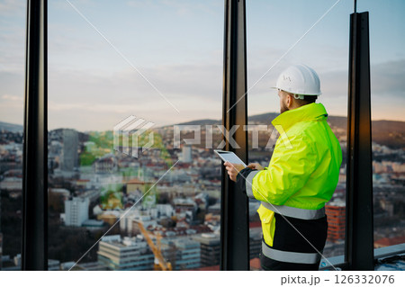 Engineer overseeing city construction project, reading documentation. Engineer overseeing city construction project, reading documentation. 126332076