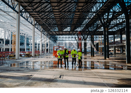 Team of engineers and construction workers inspecting building progress. Team of engineers and construction workers inspecting building progress. 126332114