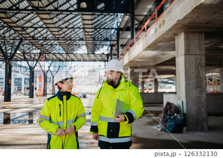 Engineers discussing construction plans using a tablet on site. Engineers discussing construction plans using a tablet on site. 126332130